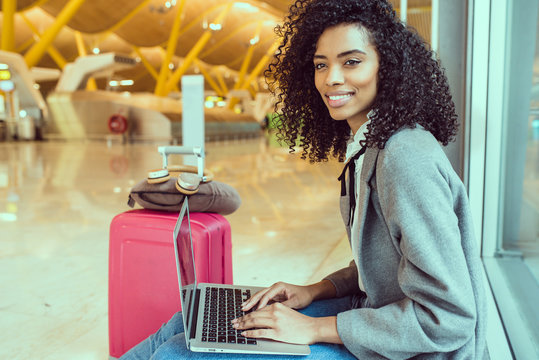 Black Woman Working With Laptop At The Airport Waiting At The Window