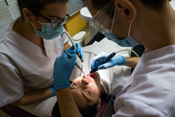 Dentist providing surgery for female client with assistant help in hospital.