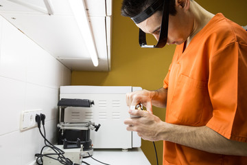 Side view of orthodontist making artificial jaw standing in hospital.