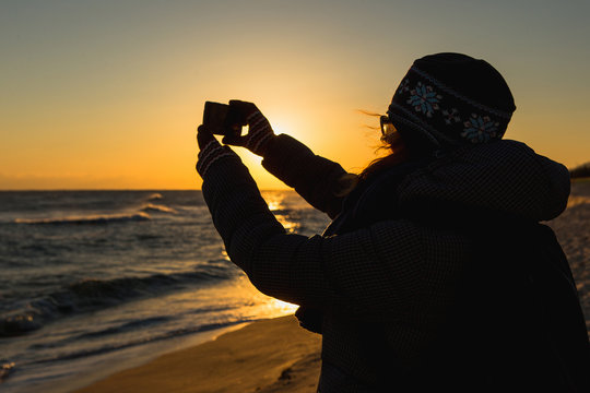 Woman takes a picture on phone. South Korea, Gangneung, coast of Japan sea.