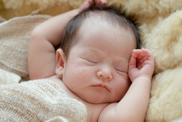 Newborn baby girl is sleeping on fur blanket