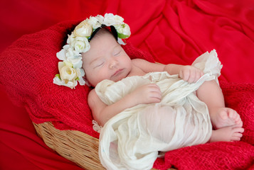 Fototapeta na wymiar Newborn baby girl is sleeping on red fabric blanket