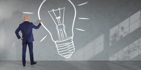 Businessman drawing a lightbulb on a wall 3D rendering
