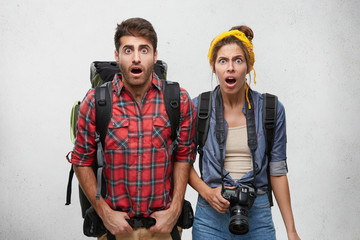 Obraz na płótnie Canvas Picture of surprised hipsters make and female in casual clothes having shocked expressions on their faces standing against white studio wall background with copy space for your text or information