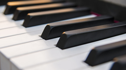 Dettaglio dei tasti di un pianoforte antico ma ristrutturato e rimesso a nuovo. La tastiera è composta da 88 tasti, di colore bianco e nero, sui quali si riflettono i colori caldi del tramonto.