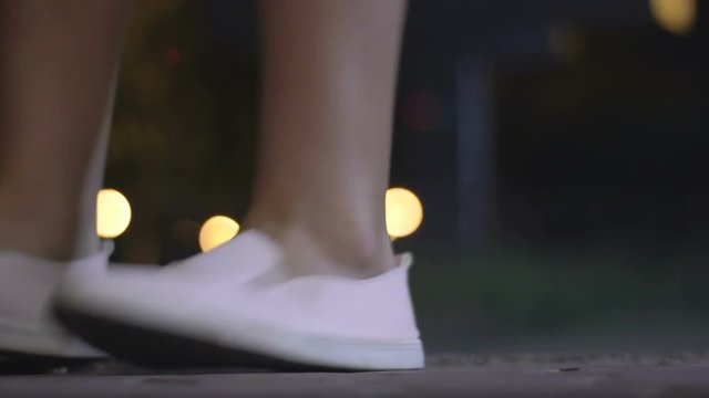 The girl moves happily to the rhythm. Teenager at night in the park. close-up of dancing female feet
