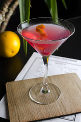 Cocktail cosmopolitan on black table with palm tree on background