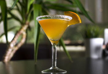 Cocktail sidecar on black table with palm tree on background