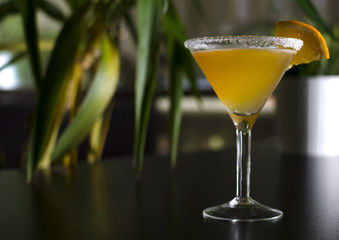 Cocktail sidecar on black table with palm tree on background