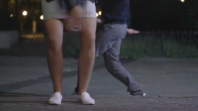 Man and woman happily move to rhythm. Teenagers have fun at night in the park. a girl and a guy dancing funny