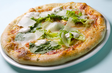 Caesar pizza on a white plate on a blue background