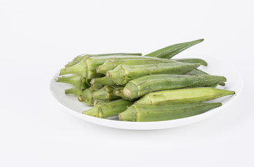 Fresh young okra on a white plate.