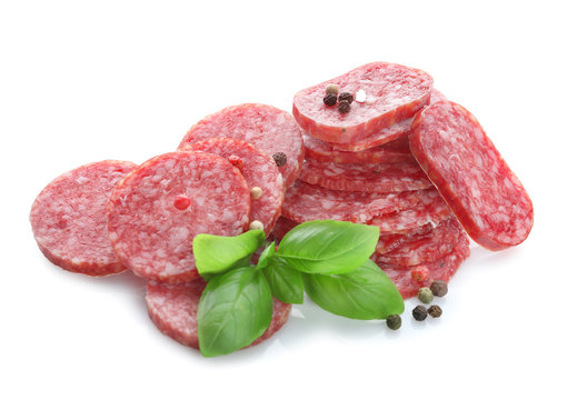 Delicious sliced sausage with basil and peppers on white background