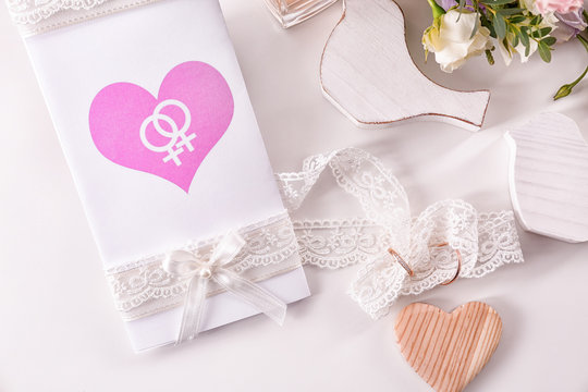Invitation card and rings for lesbian wedding on table