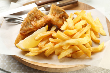 Tasty fried fish and chips on wooden board