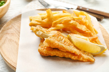 Tasty fried fish and chips on wooden board