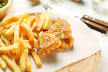 Tasty fried fish and chips on wooden board