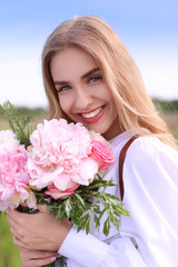 Beautiful young woman with bouquet of peonies, closeup