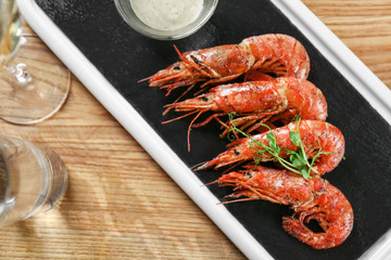 Slate plate with delicious shrimps on table