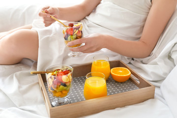 Obraz na płótnie Canvas Young woman having tasty breakfast on bed