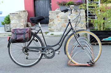 Fototapeta na wymiar Vélo pour femmes de la ville garé dans un parking à vélos près de la maison, sacoche de vélo élégante en cuir