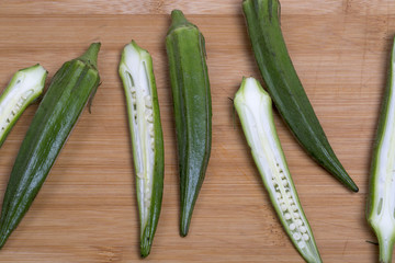 Fresh okra on the wooden table, top view.