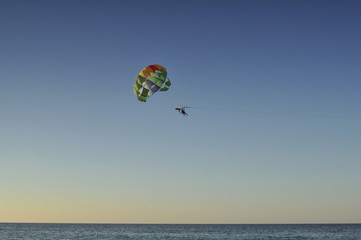 Fototapeta na wymiar Люди летят на парашюте над морем на закате