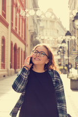 Fototapeta premium Modern girl talking on her cellphone outdoors.