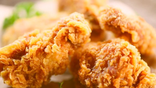 Fried chicken wings and legs on wooden table. Closeup of tasty fried chicken. Rotation 360 degrees. 4K UHD video footage. Ultra high definition 3840X2160