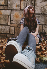 Preciosa chica adolescente sentada en el suelo en un parque en otoño 