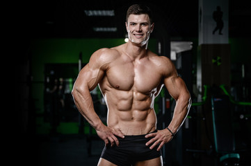 Obraz na płótnie Canvas Muscular handsome athletic bodybuilder fitness model posing after exercises in gym on diet .