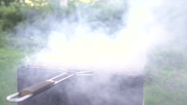 Two boys play near a grill with burning wood