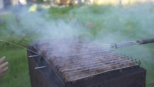 Two boys play near a grill with burning wood