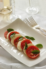 Caprese salad with ripe tomatoes and mozzarella cheese with fresh basil leaves. Italian food.