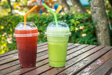 Iced green tea and iced lemon tea with straw in a plastic glass on natural background.
