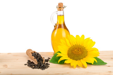 Sunflower oil, seeds and flower on wooden table with white background
