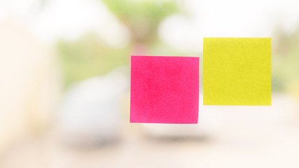 Yellow and pink reminder sticky note on glass, empty space for text with light from window