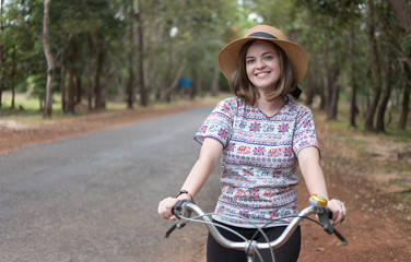 Obraz premium Cute young white girl on a bicycle ride on the road in the park