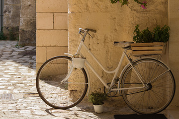 Fototapeta na wymiar white bike and crate in a sunny street of matera