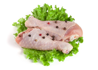 Two raw chicken drumsticks with lettuce leaf isolated on white background