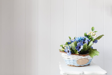 Wicker basket with artificial flowers with the inscription. beautiful blue bouquet of faux flower in a basket placed on a wooden table