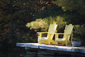 Yellow Adirondack chairs  on lakeside dock