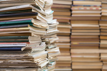 A stack of old school notebooks and a stack of textbooks or books.
