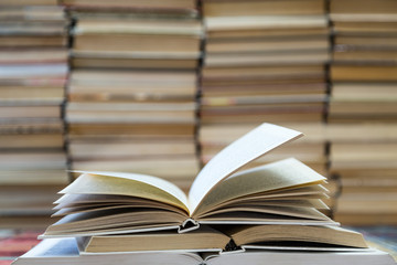 A stack of books with colorful covers. The library or bookstore. Books or textbooks. Education and reading. Open book in the foreground.
