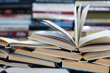 A stack of books with colorful covers. The library or bookstore. Books or textbooks. Education and reading. Open book in the foreground.