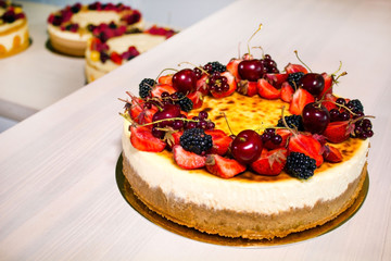 Big sweet cakes with many different fruits on kitchen
