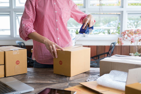 business owner packing cardboard box at workplace. freelance woman seller prepare parcel box of product for deliver to customer.  Online selling, internet marketing, e-commerce, shipping concept