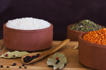 White rice, red lentils and green peas mache on wooden tray. Bay leaves and black peppercorns in wood spoon.