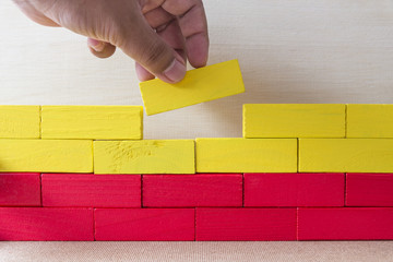 Two fingers put the last red block on the wall, Metaphoric scene,Building concept