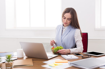 Young business woman eating salad at office